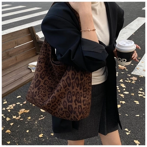Close-up of large leopard print bucket bag on a park bench in an autumn setting