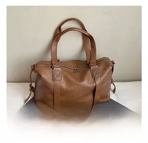 Detail of a brown PU leather large tote bag with zipper closure on a white surface