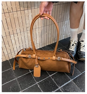 Detail of dark brown suede bowling bag with silver buckles and long straps
