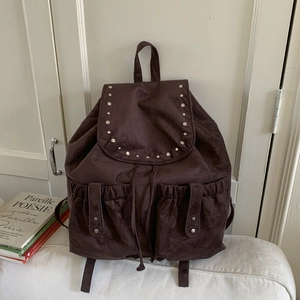 Detailed view of coffee brown suede backpack with silver studs and drawstring closure