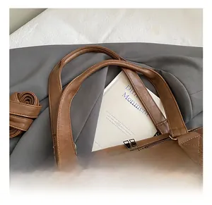 Detail of dark brown PU leather travel bag with reinforced handles and silver metal zippers