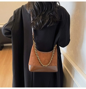 Brown vintage baguette bag with gold chain and mixed texture leather detail shown on model