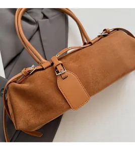 Detailed view of brown suede Boston bag on grey blazer with smooth leather handles