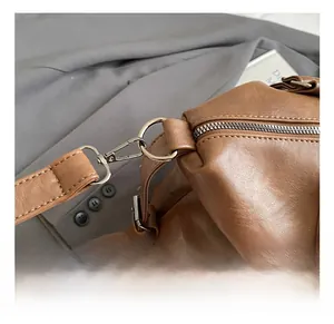 Close-up of premium silver metal swivel hooks and smooth zipper on brown tote bag