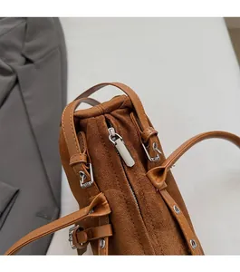 Detailed macro view of smooth silver zipper and brown suede texture on baguette shoulder bag