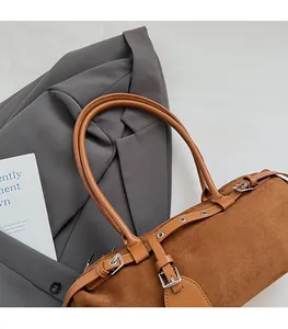 Close-up of brown suede baguette bag with silver buckle on a stylish office outfit