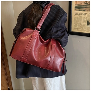 Detailed view of dark burgundy PU leather tote bag with wide shoulder strap on model