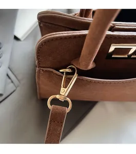 Detail of high-quality gold hardware and lobster clasp on brown suede small square bag