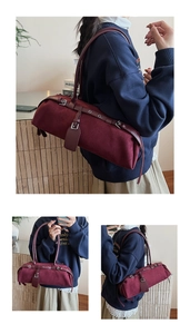 Detail of burgundy suede cylindrical shoulder bag featuring silver metal buckle and long strap