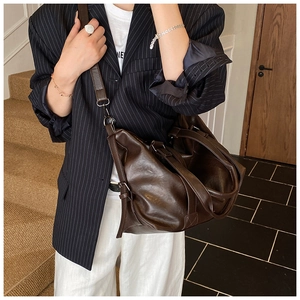 Close-up of deep brown soft PU leather tote bag with stylish metallic buckle details