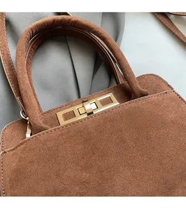 Detailed macro shot of the golden metal lock and brown suede texture on the retro handbag