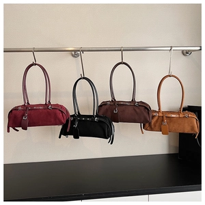 Various colors of suede baguette underarm bags hanging on a display rack in a shop