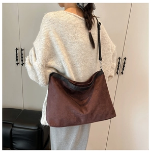 Detailed side view of large brown vintage hobo shoulder bag worn by a model