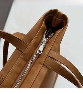 Detail of smooth metal zipper and brown leather texture on a spacious tote bag