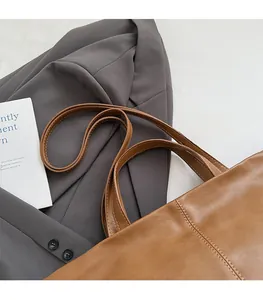 Detail of comfortable shoulder straps and fine stitching on a brown leather tote bag