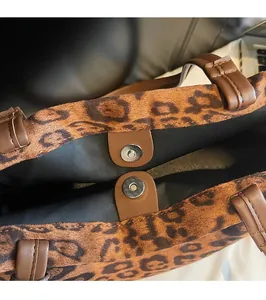 Détail du fermoir magnétique argenté sur un sac fourre-tout léopard avec poignées brunes