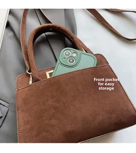 Detail of vintage brown suede crossbody bag featuring a functional front phone pocket