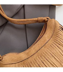 Détail d'un sac bandoulière en daim marron avec franges fines et coutures de qualité