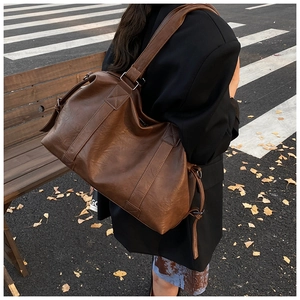 Detailed view of deep brown large leather tote bag worn by a model in autumn street style
