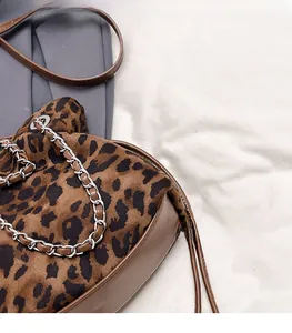Detail of leopard print faux fur tote bag featuring brown leather straps and metal chain