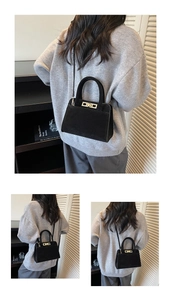 Detail view of black suede tote with gold rectangular clasp and adjustable shoulder strap