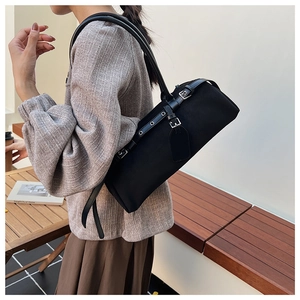 Detail of a black leather underarm bag featuring silver hardware and dual slim straps