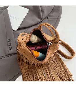 Vue détaillée de l'intérieur spacieux du sac à franges marron avec cosmétiques et portefeuille