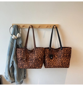 Détail de grands sacs cabas léopard avec anses marron et noires sur des crochets