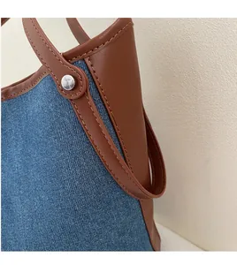 Close-up of denim and brown leather stitching with silver rivets on a bucket bag