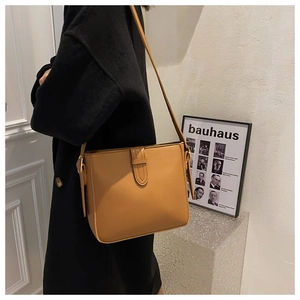 Karamellfarbene Ledertasche gestylt auf schwarzem Mantel für den eleganten Alltag