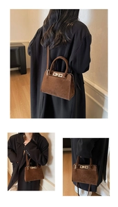Detailed view of large dark brown suede tote with gold hardware and removable shoulder strap