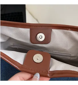 Detail of the brown leather tote interior with magnetic buckle and herringbone lining