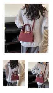 Close-up of vintage burgundy suede handbag with golden turn-lock and handle detail