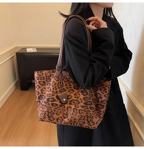 Détail du sac cabas léopard avec anses marron porté par un mannequin dans une pièce