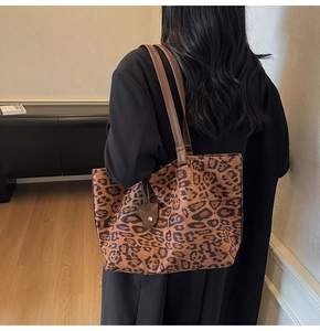Détail du grand sac cabas en daim léopard avec anses en cuir porté par un mannequin