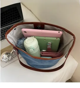 Top view of spacious denim bucket bag interior filled with tablet, umbrella, and wallet