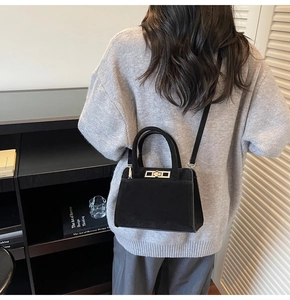 Model view of a vintage black matte crossbody bag with golden metal twist lock detail
