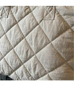Détail du motif à losanges matelassé sur un sac cabas beige avec coutures blanches