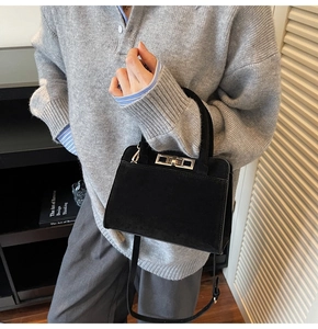 Détail du sac à bandoulière noir mat avec fermoir rotatif argenté porté par le modèle