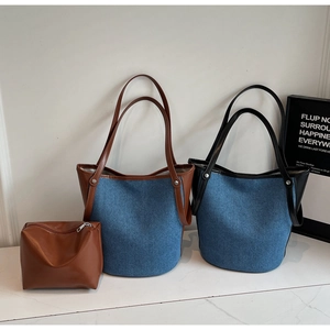 Detail of denim tote bags with leather handles and metallic rivet reinforcement accents