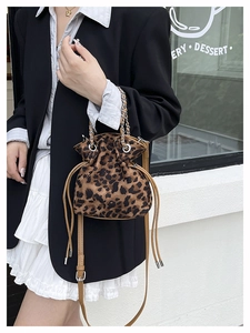 Detail of leopard print bucket bag featuring a drawstring closure and metal chain handle