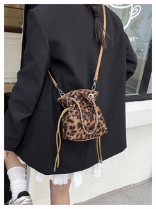 Detail of leopard print bucket bag with yellow leather strap and chain accent