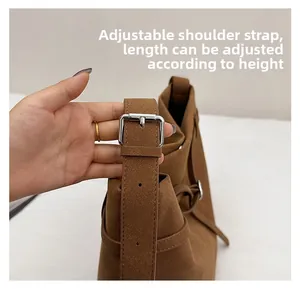 Detail of adjustable suede shoulder strap with silver metal buckle on brown tote bag