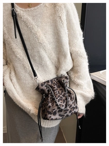 Detail view of leopard print drawstring bucket bag with gold chain and crossbody strap