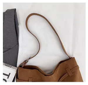 Macro detail of brown suede tote bag featuring slim shoulder straps and metallic hardware