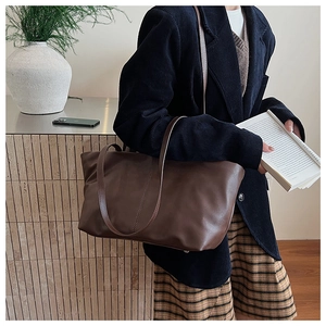 Detail of a large brown matte leather tote bag styled with a minimalist vintage aesthetic