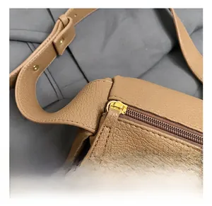 Close-up of golden zipper hardware on brown lychee pattern leather crossbody bag