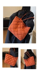 Detailed view of quilted stitching on orange puffer tote bag with long shoulder straps