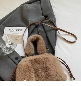 Vue détaillée du sac seau marron en fausse fourrure avec bandoulière sur fond décoratif chic