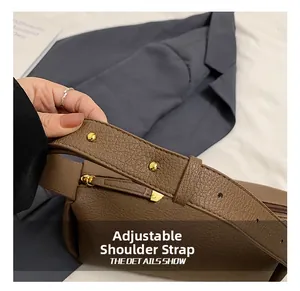 Detail of adjustable strap with gold-tone hardware on brown lychee texture leather bag